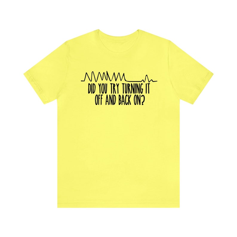 May include: A yellow t-shirt with black text that reads "DID YOU TRY TURNING IT OFF AND BACK ON?" above a line graph design. The shirt is a solid, bright yellow color.