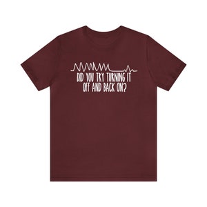 May include: A maroon t-shirt with white text and a graphic of a heartbeat line. The text reads, "DID YOU TRY TURNING IT OFF AND BACK ON?" This shirt is a humorous take on tech support.