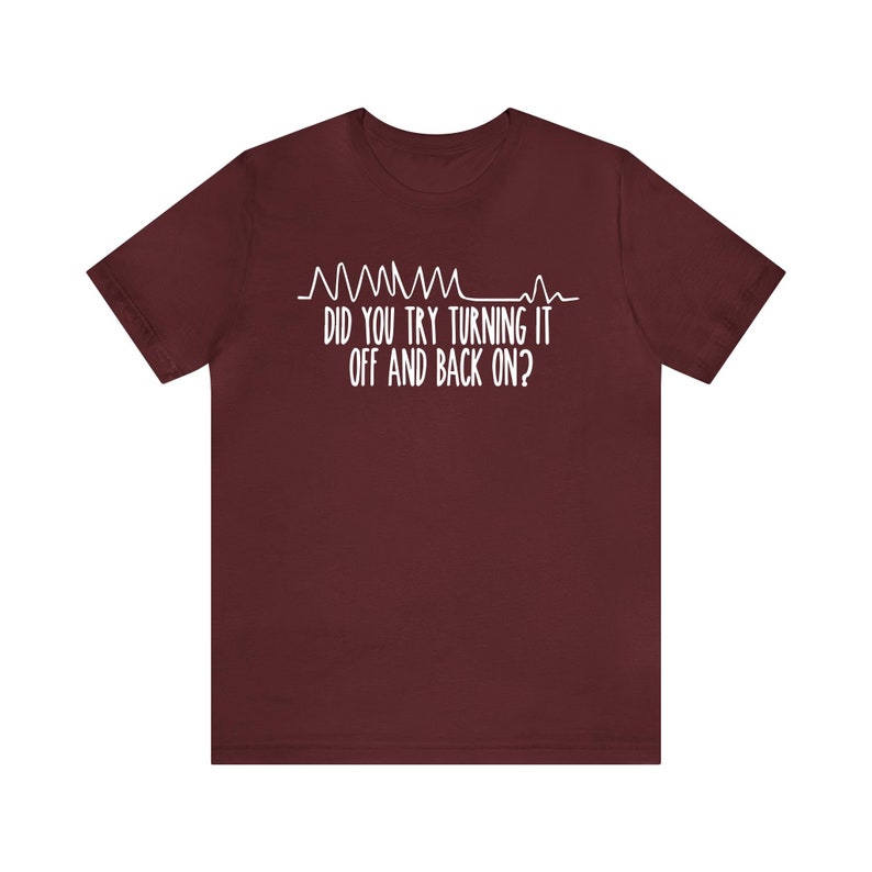 May include: A maroon t-shirt with white text and a graphic of a heartbeat line. The text reads, "DID YOU TRY TURNING IT OFF AND BACK ON?" This shirt is a humorous take on tech support.