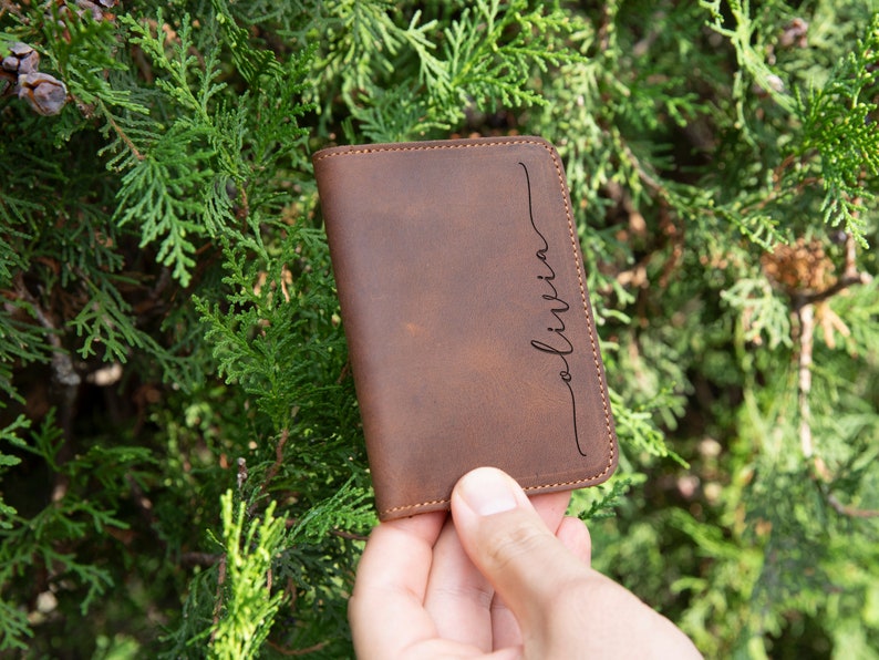 May include: A brown leather wallet with the name "Olivia" engraved on the front.