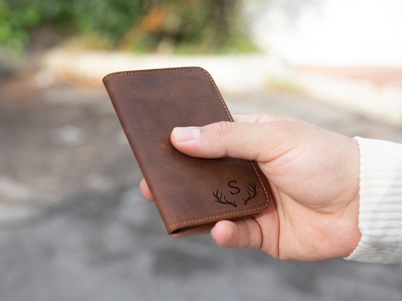May include: A brown leather wallet with a small, engraved design of antlers and the letter "S".