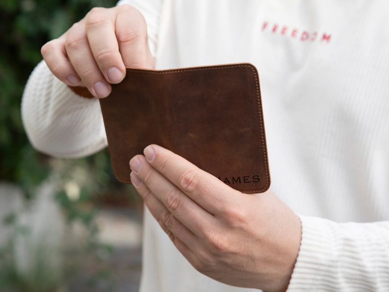 May include: A brown leather wallet with the name "JAMES" embossed on the front.