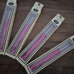 Peut inclure: Quatre paquets de crochets ETIMO Rose. Chaque paquet est dans une boîte crème avec une fenêtre transparente montrant un crochet rose. Les boîtes sont étiquetées avec la taille du crochet, comme 4,50 mm.