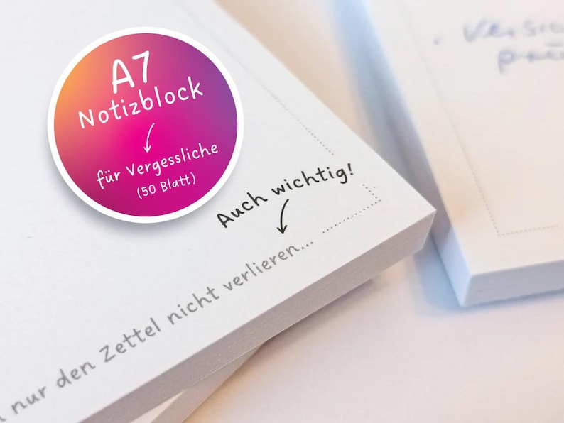 May include: A close-up of a stack of white memo pads with a pink and orange sticker that says "A7 Notizblock f&uuml;r Vergessliche (50 Blatt)". The top memo pad has handwritten text that says "Auch wichtig! nur den Zettel nicht verlieren..."