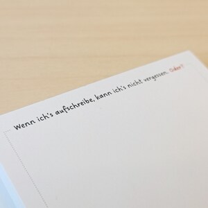May include: A white notepad with the text "Wenn ich's aufschreibe, kann ich's nicht vergessen. Oder?" written on it.
