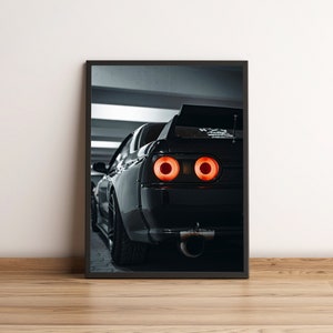 Könnte beinhalten: Gerahmter Druck eines schwarzen Sportwagens, von hinten gesehen, mit leuchtend roten Rücklichtern. Das Auto hat einen großen Spoiler und ein markantes Auspuffrohr. Das Bild ist vor einem neutralen Hintergrund.