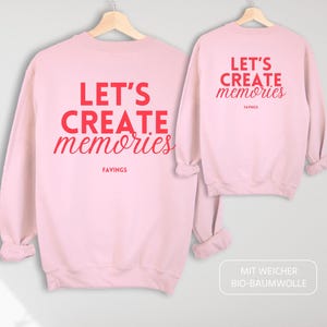 Op de afbeelding: Roze sweatshirt met de tekst "Let's Create Memories" in rode letters. De sweatshirt is gemaakt van zacht biologisch katoen.