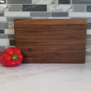 May include: A rectangular wooden cutting board with a dark brown wood grain pattern.