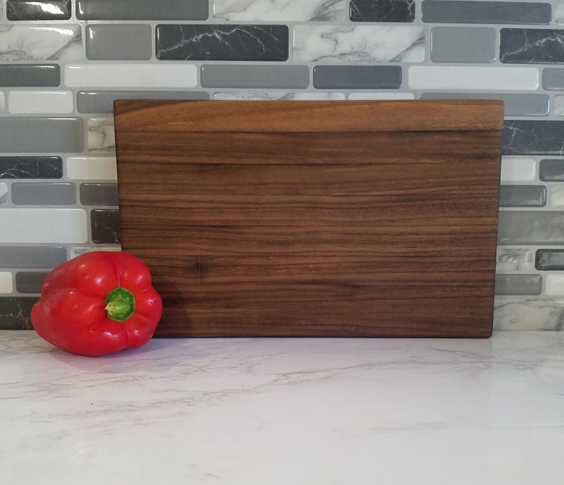 May include: A rectangular wooden cutting board with a dark brown wood grain pattern.