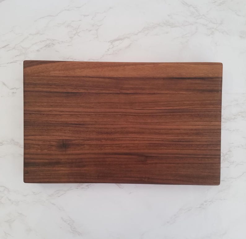 May include: A rectangular wooden cutting board with a dark brown wood grain finish.
