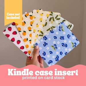 May include: A collection of Kindle case inserts with various fruit patterns, including strawberries, oranges, lemons, pickles, and blueberries. The inserts are printed on card stock. The text "Case not included" is visible in a yellow rectangle.