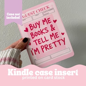 May include: A pink Kindle case insert printed on card stock. The insert features the text "BUY ME BOOKS & TELL ME I'M PRETTY" in red, with heart accents. The design resembles a guest check.