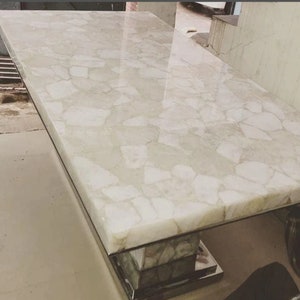 May include: A white table top with a unique design made of small white stones. The table top is made of a smooth, polished material and has a modern, contemporary look.