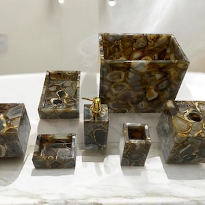 Puede incluir: Un juego de baño de seis recipientes de piedra de ágata marrón y dorada. El juego incluye un dispensador de jabón, un portacepillos de dientes, un vaso y tres bandejas.