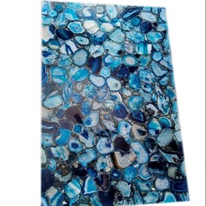 May include: Blue agate slab with a polished surface. The slab is made up of many small, round pieces of agate, each with a different shade of blue. The agate is a natural stone and has a unique pattern.
