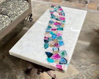 May include: A white coffee table with a unique design featuring a long, curved line of colorful agate slices embedded in the surface.