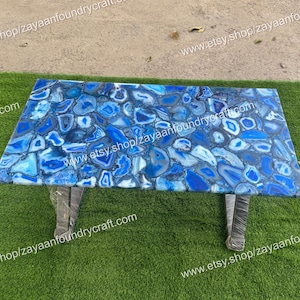 May include: A blue agate table top with a unique pattern of blue and white agate slices. The table top is supported by two metal legs.
