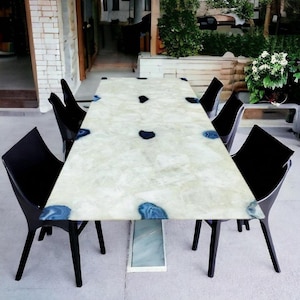 May include: A white rectangular dining table with a blue agate inlay top. The table is surrounded by six black chairs.