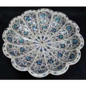 Puede incluir: Un cuenco de mármol blanco con un borde festoneado y diseños florales intrincados incrustados con nácar y piedras azules.