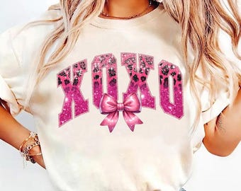 May include: White t-shirt with a pink glitter XOXO graphic and a pink bow.