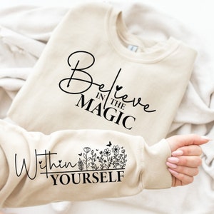 May include: Beige sweatshirt with the text "Believe in the Magic" on the front and "Within Yourself" with a floral design on the sleeve.