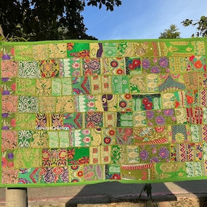 Könnte beinhalten: Ein Patchwork-Quilt mit einer Mischung aus grünen Stoffen, mit floralen und geometrischen Mustern. Der Quilt hat einen grünen Rand und zeigt den Text "Sarvaya Creation".