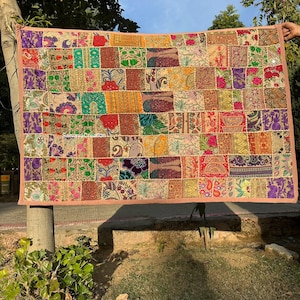May include: A patchwork quilt with a variety of colors and patterns, including floral, geometric, and paisley designs. The quilt is made of different fabrics and has a beige background.