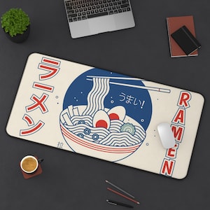 Könnte beinhalten: Eine weiße und blaue illustrierte Ramen-Schüssel mit Essstäbchen und dem Text "Ramen" und "う ま い!" auf beigefarbenem Hintergrund. Der Text "ラーメン" befindet sich auch auf der linken Seite des Bildes.
