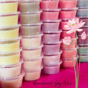 May include: A collection of small, clear plastic containers filled with wax in shades of yellow, beige, pink, and purple. The text "Handmade Soy Wax" is at the bottom. A pink lotus flower is on the right.