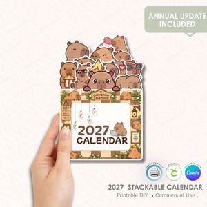 May include: A 2027 printable calendar featuring a collection of cartoon capybaras in various poses, including some wearing sunglasses, eating popcorn, and using a laptop. The design includes hanging light bulbs, floral accents, and the text 2027 CALENDAR.