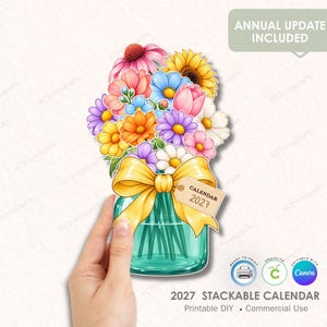 Puede incluir: Una ilustración digital de un frasco de vidrio color verde azulado lleno de un colorido ramo de girasoles, margaritas y tulipanes. Un gran lazo amarillo está atado alrededor del frasco, con una pequeña etiqueta con el texto CALENDAR 2027.