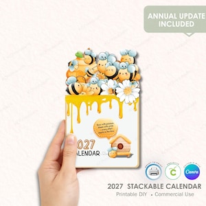 May include: A stackable 2027 calendar featuring a bee theme. The calendar has a white background with yellow dripping accents, cartoon bees, daisies, and a small house illustration. The text "027 CALENDAR" is visible.