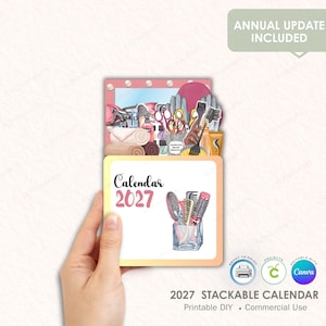 May include: A 2027 stackable calendar with a beauty theme, held by a hand. The calendar features illustrations of hair styling tools and the text "Calendar 2027". The top section includes the text "Annual Update Included".