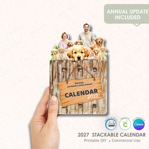 May include: A stackable 2027 calendar featuring a wooden fence with a sign that reads "BEWARE: ADORABLE DOGS AHEAD! CALENDAR 2027." The calendar has illustrations of Golden Retrievers and puppies. The words "ANNUAL UPDATE INCLUDED" are at the top.