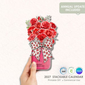 May include: A Valentine's Day-themed 2027 stackable calendar featuring a bouquet of red roses in a pink jar with a bow. The bow is white with red hearts. The text "ANNUAL UPDATE INCLUDED" is at the top.