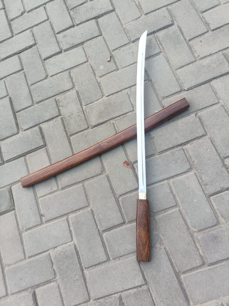 May include: A Japanese-style sword with a polished steel blade and a wooden handle. The sword is partially sheathed in a matching wooden scabbard. The handle and scabbard are a dark brown color.