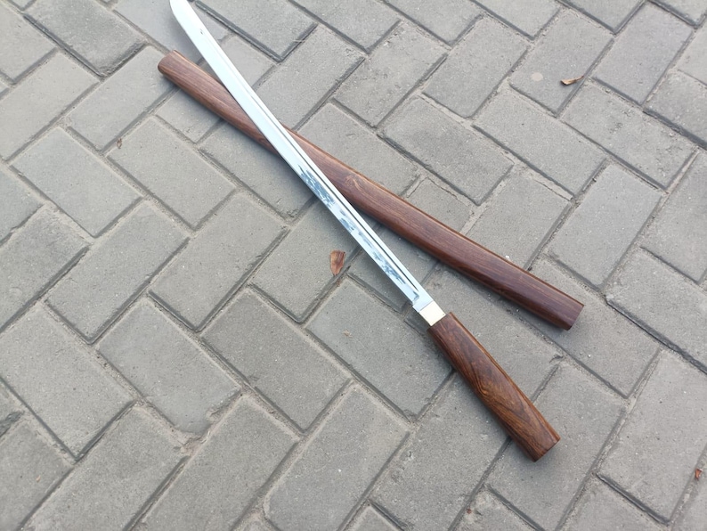 May include: A Japanese-style sword with a polished steel blade and a dark wood handle. The sword is partially unsheathed from its matching wooden scabbard. The handle and scabbard have a rich, dark brown color.