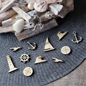 May include: A set of 10 wooden nautical themed cutouts, including a sailboat, anchor, compass, lighthouse, and seagull. The cutouts are on a gray textured surface.