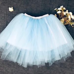 May include: A light blue tulle tutu skirt with a white waistband.