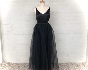 Op de afbeelding: Een zwarte tule rok met een satijnen lijfje, gedragen door een mannequin. De rok is lang en zwierig, en het lijfje is strak.
