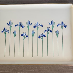 May include: Rectangular serving tray with a cream-colored surface and a gold-colored rim. The tray features a repeating pattern of blue iris flowers with green stems. The flowers are in various stages of bloom.