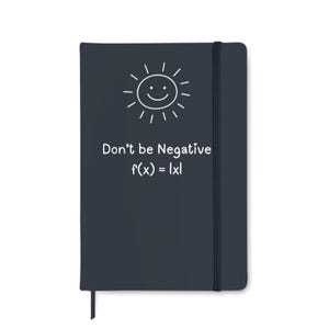 May include: A dark blue notebook featuring a smiling sun graphic and the text "Don't be Negative f(x) = |x|". It has a black elastic band closure and a ribbon bookmark.