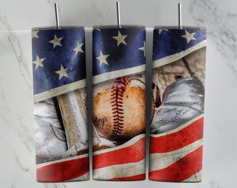 Puede incluir: Tres vasos de acero inoxidable con temática de béisbol. Cada vaso presenta un diseño de bandera estadounidense desgastada con una pelota de béisbol, un guante y un bate. Los vasos son cilíndricos y tienen una pajita plateada.