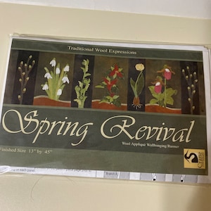 May include: A wool applique wallhanging runner pattern titled "Spring Revival" by Crane Designs. The pattern features a design of five different flowers and is 13 inches by 45 inches when finished.