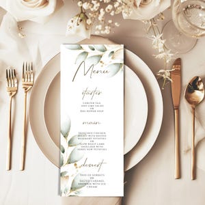 May include: A wedding menu card with a watercolor background of green leaves and gold accents. The menu includes starter, main, and dessert options.