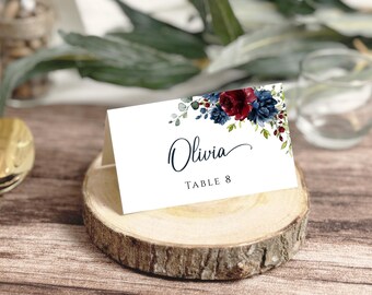 May include: White place card with a watercolour floral design in shades of blue and burgundy. The card reads "Olivia" and "Table 8".