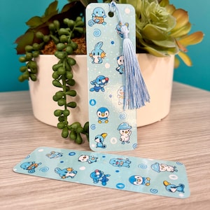 Puede incluir: Dos marcap&aacute;ginas azules con personajes de dibujos animados. Un marcap&aacute;ginas tiene una borla y una cuerda azules. Los marcap&aacute;ginas tienen un fondo azul claro con personajes de dibujos animados y remolinos. Los marcap&aacute;ginas est&aacute;n sobre una superficie de madera clara.