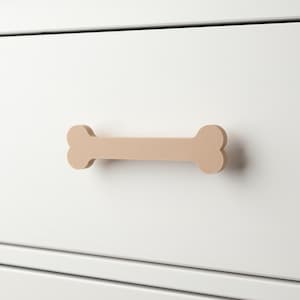 Può includere: Un cassetto di una cassettiera bianca con una maniglia in legno a forma di osso. La maniglia è di colore marrone chiaro.