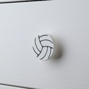 Op de afbeelding: Ronde witte kastknop met een zwart volleybalontwerp.