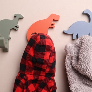 3 dinosaur wall hooks with coats on them